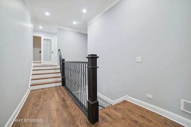 stairs featuring hardwood / wood-style floors and ornamental molding