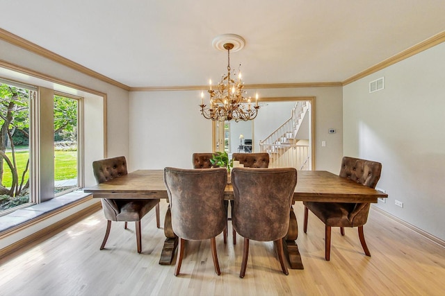 dining space featuring an inviting chandelier, ornamental molding, and light wood-type flooring