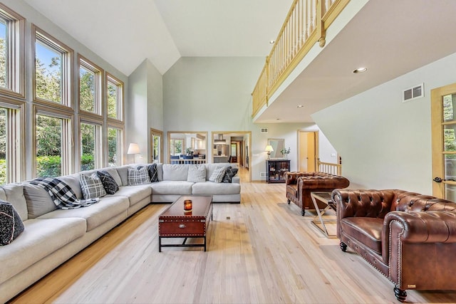 living room featuring high vaulted ceiling and light hardwood / wood-style flooring