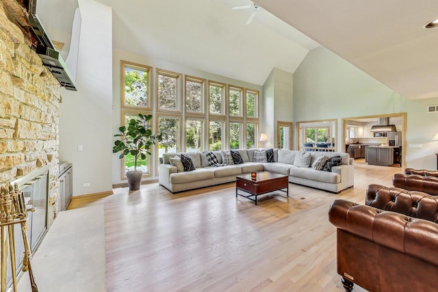 living room with a fireplace, light hardwood / wood-style flooring, and high vaulted ceiling