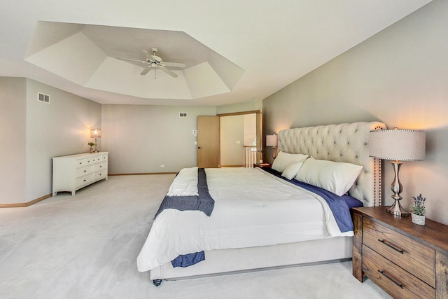 bedroom featuring light carpet, a raised ceiling, and ceiling fan