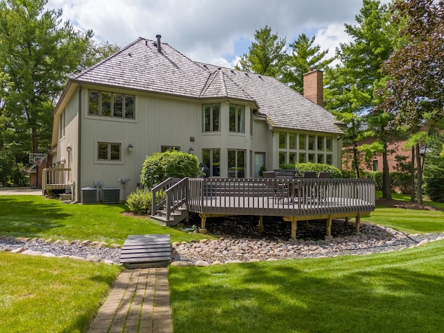 rear view of house featuring a wooden deck, central AC, and a lawn