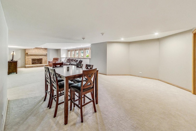 dining space featuring light carpet and a fireplace