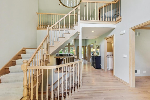 stairs featuring wood-type flooring and a high ceiling