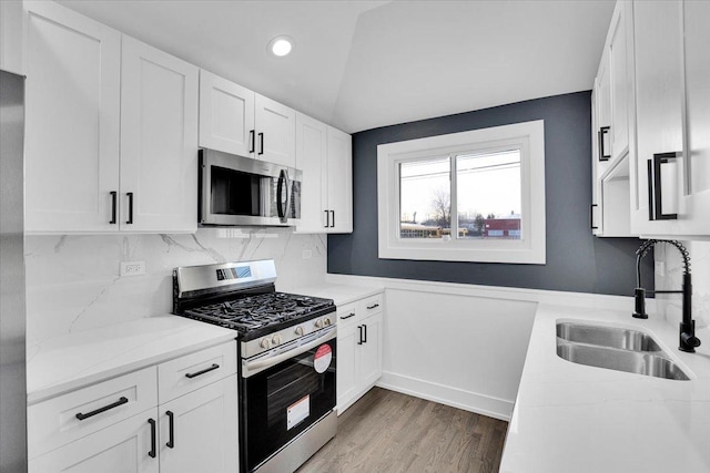 kitchen with light stone counters, appliances with stainless steel finishes, sink, and white cabinets