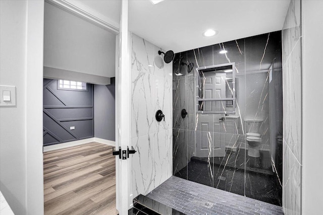 bathroom with hardwood / wood-style floors, toilet, and tiled shower