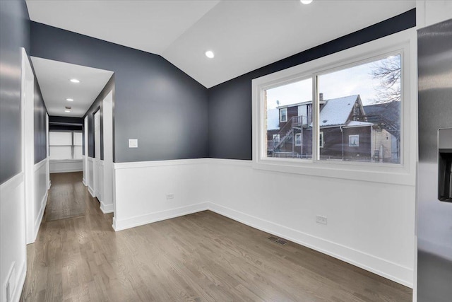 spare room featuring wood-type flooring and vaulted ceiling