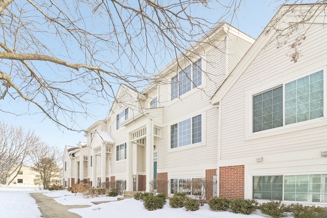 view of snowy exterior featuring brick siding