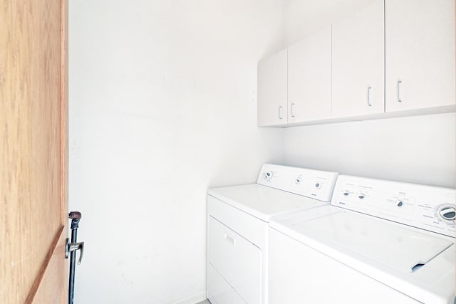 clothes washing area featuring independent washer and dryer and cabinet space