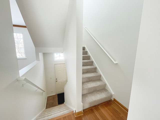 stairway featuring wood finished floors, a wealth of natural light, and baseboards