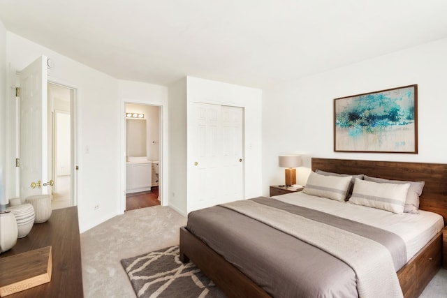 carpeted bedroom featuring a closet, baseboards, and ensuite bathroom