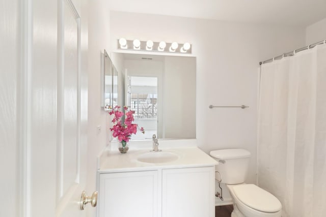 full bathroom featuring a shower with shower curtain, vanity, and toilet