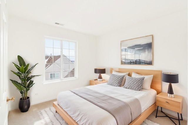 bedroom featuring baseboards, visible vents, and light colored carpet