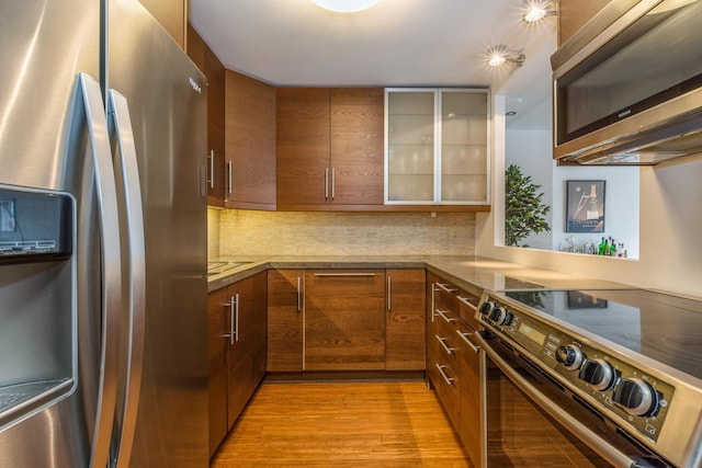 kitchen featuring decorative backsplash, light hardwood / wood-style floors, and appliances with stainless steel finishes