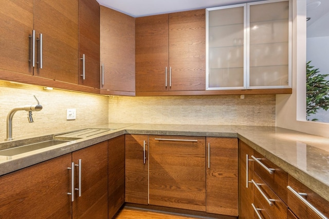 kitchen featuring tasteful backsplash, light stone countertops, sink, and light hardwood / wood-style floors