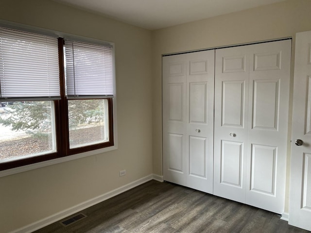 unfurnished bedroom with dark wood-type flooring and a closet