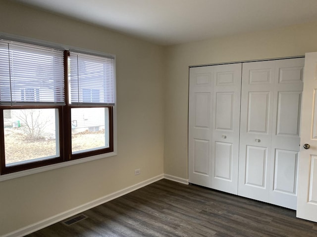 unfurnished bedroom featuring dark hardwood / wood-style flooring and a closet