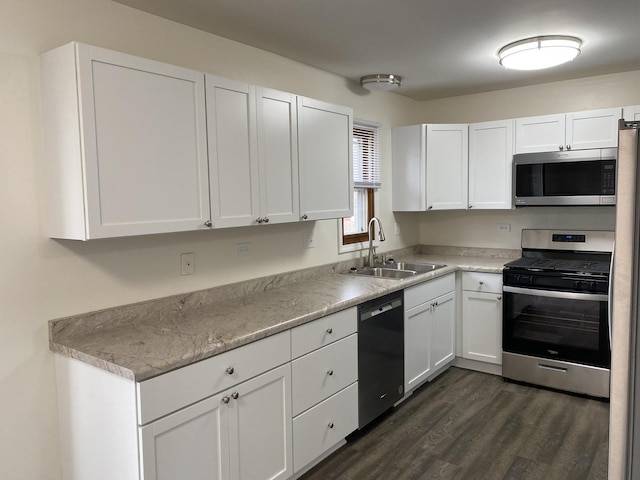 kitchen featuring sink, appliances with stainless steel finishes, white cabinetry, dark hardwood / wood-style floors, and light stone counters