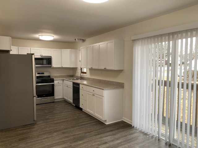 kitchen featuring white cabinetry, stainless steel appliances, dark wood-type flooring, and sink