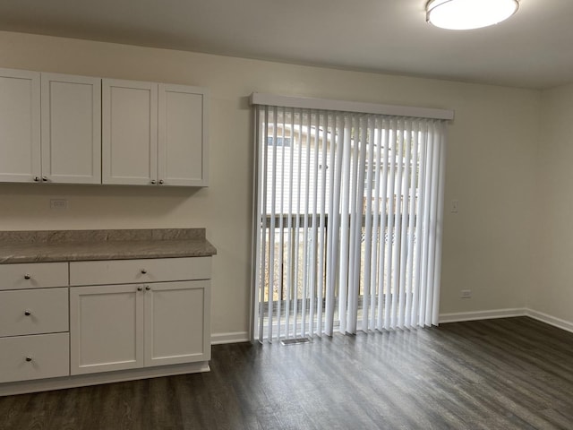 unfurnished dining area with dark wood-type flooring