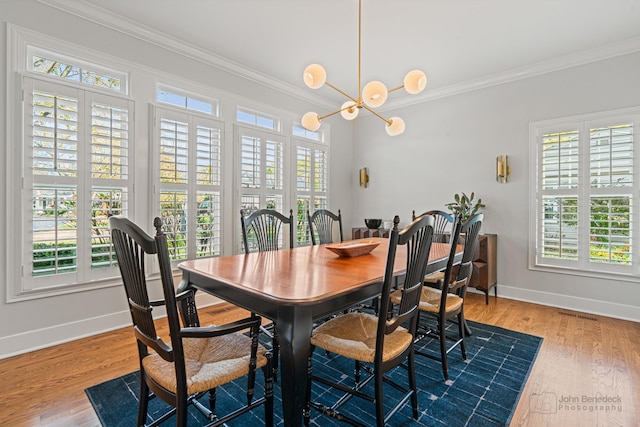 dining space featuring an inviting chandelier, ornamental molding, and hardwood / wood-style floors