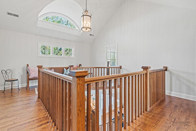 corridor featuring an inviting chandelier, hardwood / wood-style flooring, and high vaulted ceiling