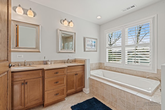 bathroom featuring tiled tub, vanity, and tile patterned flooring