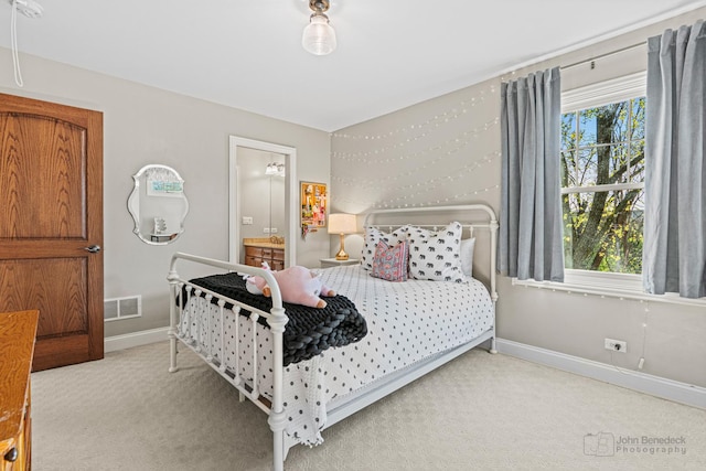 carpeted bedroom featuring multiple windows and ensuite bath