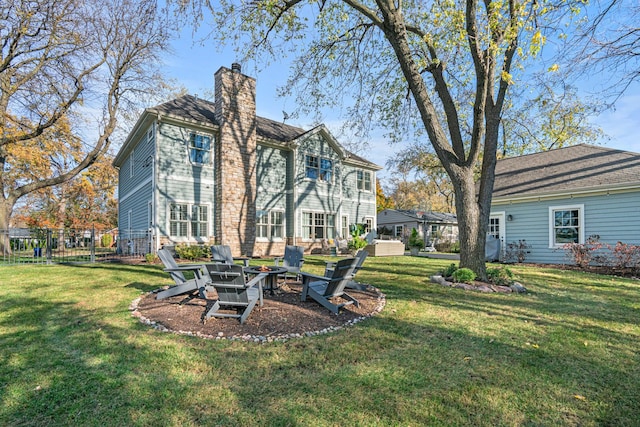 rear view of house with a yard and an outdoor fire pit