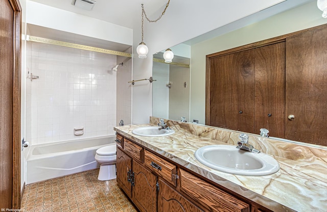 full bathroom featuring tile patterned flooring, tiled shower / bath, vanity, and toilet