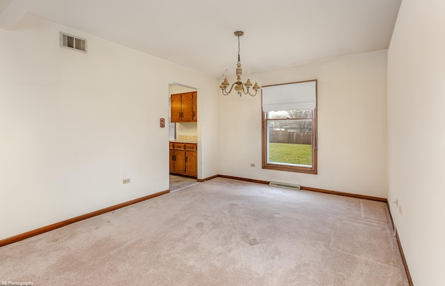 carpeted spare room with an inviting chandelier