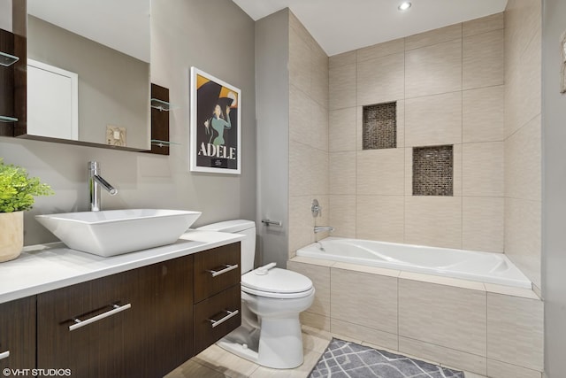 bathroom featuring vanity, a relaxing tiled tub, tile patterned floors, and toilet