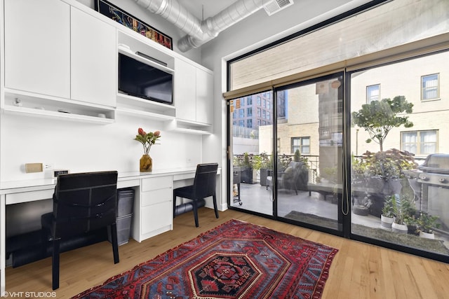 office with light hardwood / wood-style flooring and built in desk