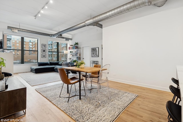 dining space with wood-type flooring and rail lighting