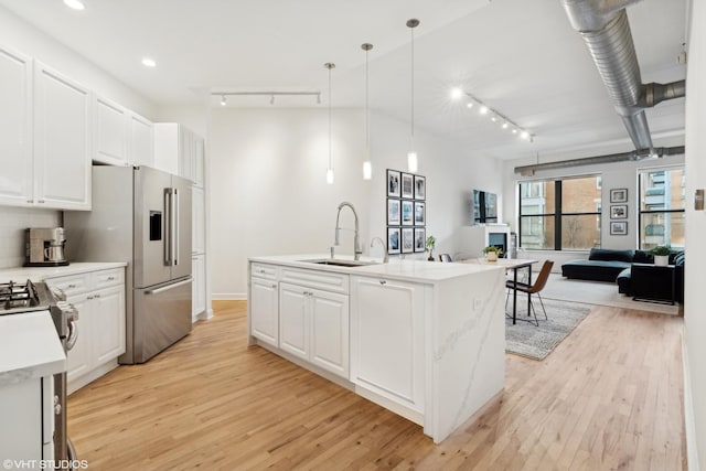 kitchen with white cabinetry, sink, pendant lighting, and an island with sink