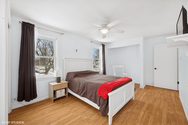 bedroom featuring light wood finished floors, multiple windows, and a ceiling fan