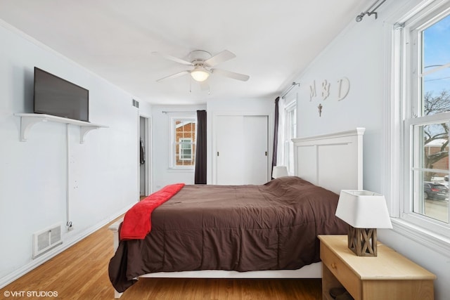 bedroom featuring ceiling fan, visible vents, crown molding, and wood finished floors