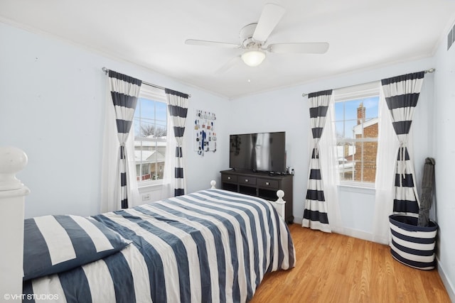 bedroom featuring ceiling fan, multiple windows, wood finished floors, and crown molding