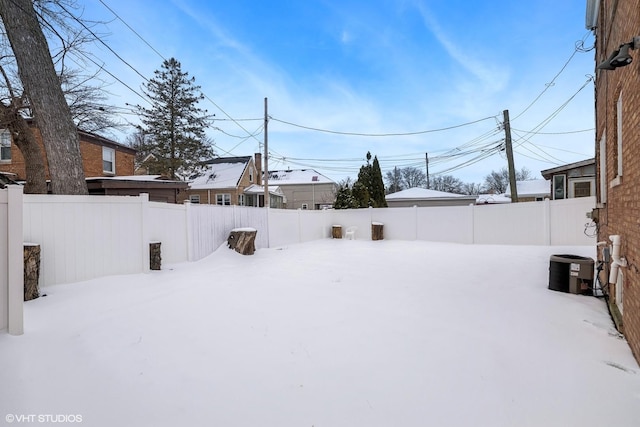 yard layered in snow featuring central air condition unit and a fenced backyard