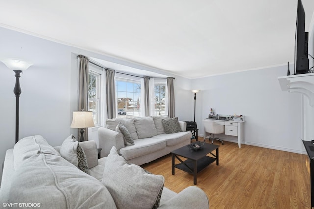 living area with ornamental molding, light wood-type flooring, and baseboards