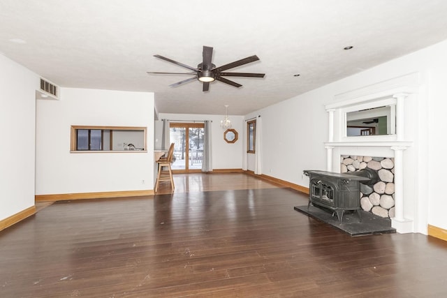 unfurnished living room featuring a wood stove, dark hardwood / wood-style floors, and ceiling fan