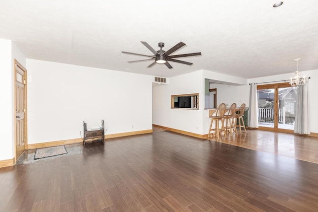 unfurnished living room featuring ceiling fan with notable chandelier and dark hardwood / wood-style floors