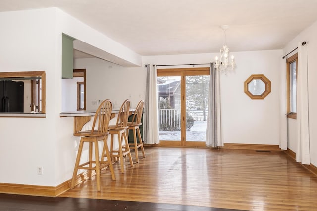 dining area featuring wood-type flooring and a notable chandelier