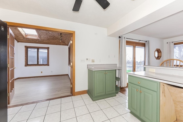 kitchen with ceiling fan, light tile patterned floors, a skylight, and green cabinetry