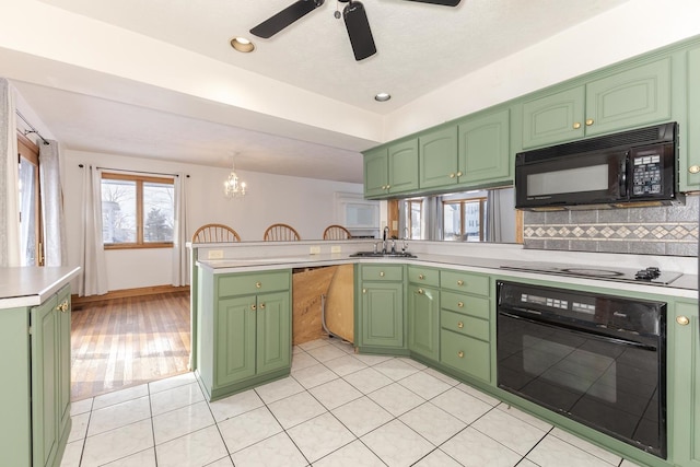 kitchen with sink, black appliances, green cabinetry, and tasteful backsplash