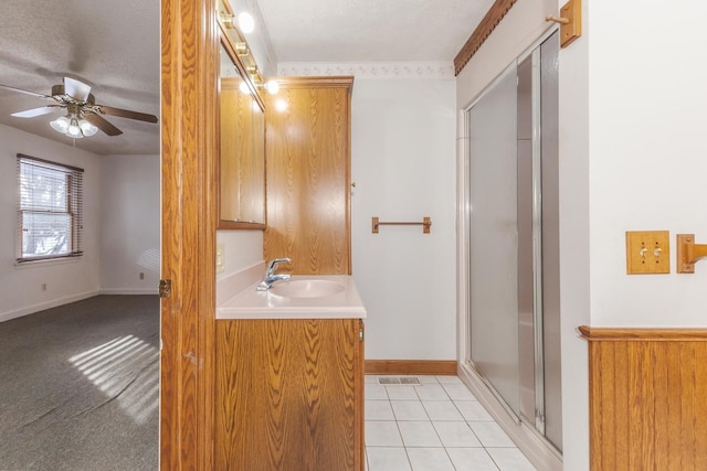 bathroom with a shower with shower door, tile patterned floors, ceiling fan, a textured ceiling, and vanity