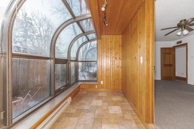 unfurnished sunroom featuring track lighting, ceiling fan, and a baseboard radiator