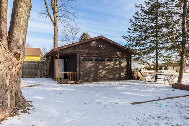 snow covered property with a garage and an outbuilding