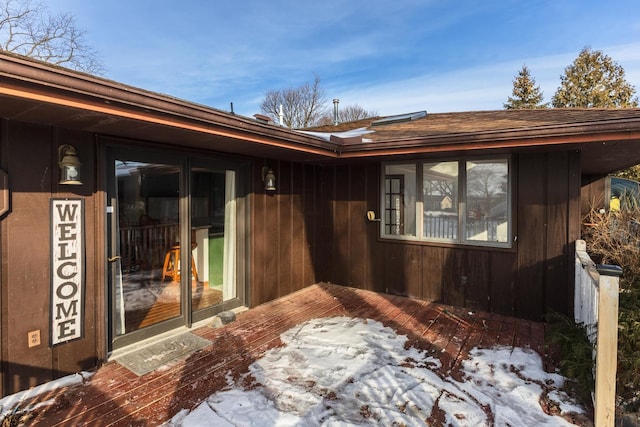 snow covered property entrance with a wooden deck