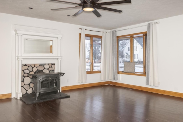 living room with a wood stove, dark wood-type flooring, and ceiling fan